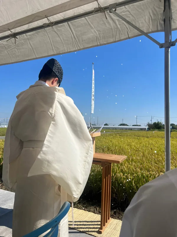 田んぼの前でご神事を行う神主